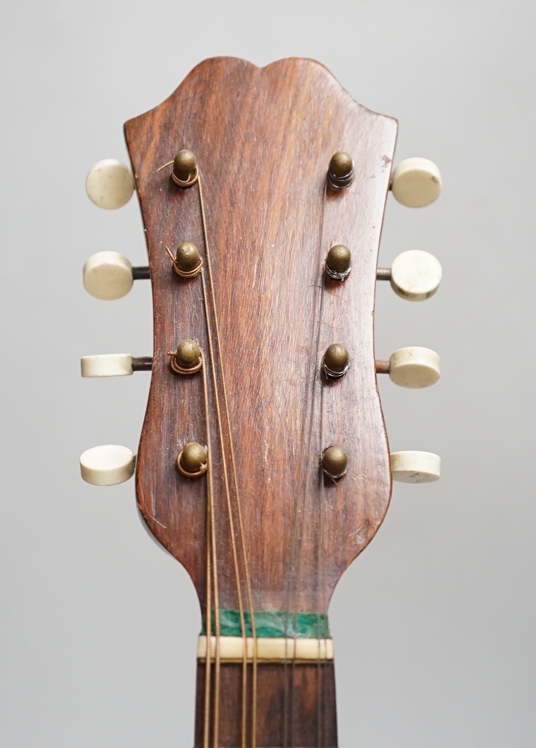 A cased mandolin with tortoiseshell detail, bone tuning pegs, 61cm long